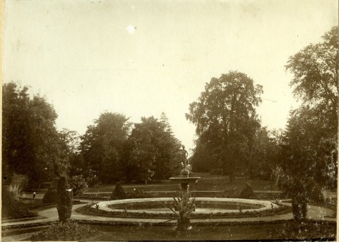 Park przy pałacu w Będlewie z alejkami widziany w dzień. Na godzinie szóstej fontanna.